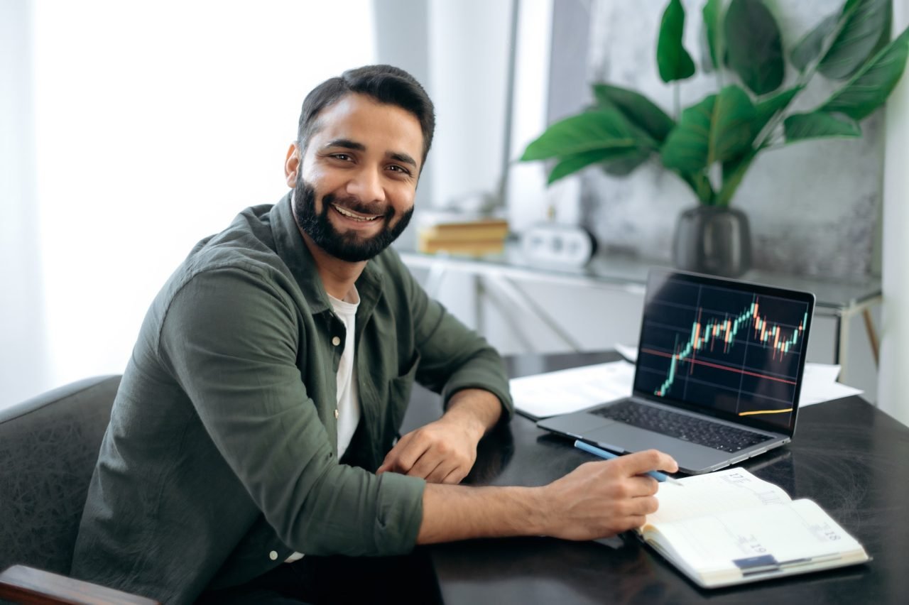 Portrait of a positive successful Indian or Arabian trader, stock market broker, investor, sitting